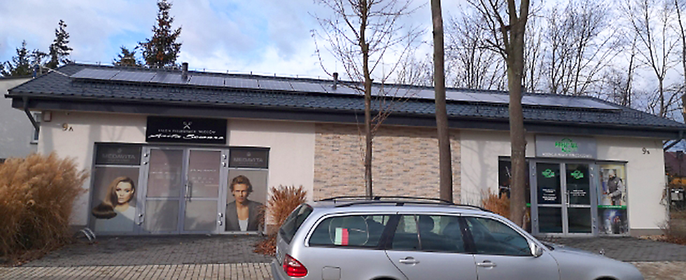 Budynek salonu fryzjerskiego AS Szwarc w Kościanie z zamontowanymi panelami fotowoltaicznymi.
